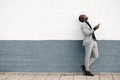 Full body laughing african american businessman by wall holding mobile phone Royalty Free Stock Photo