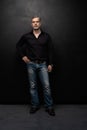 Full body portrait of middle-aged good looking man posing in front of a black background with copy space. Royalty Free Stock Photo