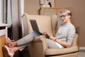 Full body portrait of pretty smart woman about 30s in casual clothes sitting in a chair writing in laptop Royalty Free Stock Photo