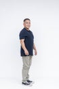 Full body portrait of a self-assured middle-aged Asian man in casual attire standing against a white background Royalty Free Stock Photo