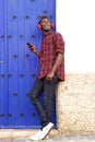 Full body smiling african man with mobile phone and headphones looking away Royalty Free Stock Photo