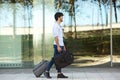 Full body smiling handsome man walking outside with suitcase Royalty Free Stock Photo