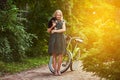 Full body portrait of a smiling little blonde girl in a casual dress, holds cute spitz dog. Ride on a bicycle in the Royalty Free Stock Photo