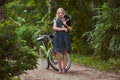 Full body portrait of a smiling little blonde girl in a casual dress, holds cute spitz dog. Ride on a bicycle in the Royalty Free Stock Photo