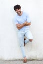 Full body smiling male fashion model leaning against white wall Royalty Free Stock Photo