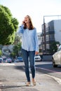 Full body smiling woman walking and talking with mobile phone Royalty Free Stock Photo