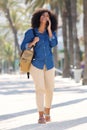 Full body smiling woman walking and talking outside on mobile phone Royalty Free Stock Photo