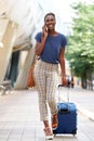 Full body young african american woman walking in city with luggage and talking on mobile phone Royalty Free Stock Photo