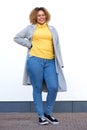 Full body young african american woman in winter coat smiling against white wall Royalty Free Stock Photo