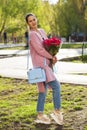 Portrait of a young beautiful woman with a bouquet of red roses in spring park Royalty Free Stock Photo