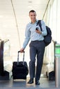 Full body young businessman walking with travel bags and mobile phone Royalty Free Stock Photo