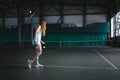 Full body portrait of young girl tennis player in action in a tennis court indoor Royalty Free Stock Photo