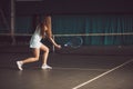 Full body portrait of young girl tennis player in action in a tennis court indoor Royalty Free Stock Photo