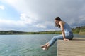 Woman resting sitting in a pier looking at lake Royalty Free Stock Photo