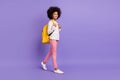 Full body profile photo of brown haired girl afro american wear pink pants bag go copyspace isolated on violet color