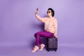 Full body profile photo of pretty lady waiting flight hold telephone sitting on bag making selfies wear hat sun specs Royalty Free Stock Photo