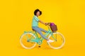 Full body profile photo of sweet millennial lady ride bicycle wear t-shirt jeans sneakers bag isolated on yellow Royalty Free Stock Photo