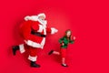 Full body profile side photo of cheerful two fairy runners santa claus elf in hat headwear carrying heavy bag with Royalty Free Stock Photo