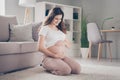 Full body profile side photo of young cheerful pregnant girl happy positive smile hold belly sit floor home Royalty Free Stock Photo