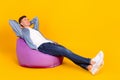 Full body profile side photo of young man sit purple chair hands behind head drowse isolated over yellow color