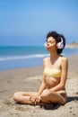 Young African American woman in headphones practicing yoga on beach Royalty Free Stock Photo