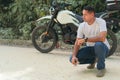 Full body of a serious young ethnic biker in casual clothes near the motorcycle