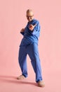 Full body shoot of funny man in pajama playing imaginary guitar over pastel rose background. Royalty Free Stock Photo