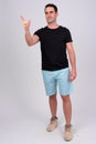 Full body shot of happy handsome man smiling while pointing finger Royalty Free Stock Photo