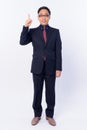 Full body shot of happy Japanese businessman in suit pointing up Royalty Free Stock Photo