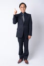 Full body shot of happy Japanese businessman in suit pointing up Royalty Free Stock Photo