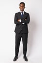 Full body shot of happy young African businessman smiling with arms crossed Royalty Free Stock Photo