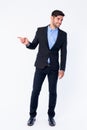 Full body shot of happy young bearded Persian businessman pointing to side and looking away Royalty Free Stock Photo