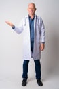 Full body shot of mature handsome bald man doctor showing something