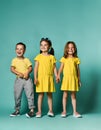 Full body shot of three children in bright clothes, two girls and one boy. Triplets, brother and sisters.