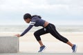 Side portrait of fit young african american woman stretching muscles at the beach