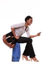 Full body side of smiling young black woman sitting on suitcase with mobile phone against white background Royalty Free Stock Photo