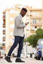 Young african businessman walking in the city with mobile phone and earphones Royalty Free Stock Photo