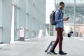 Full body side of young black man traveling with suitcase and cellphone at airport Royalty Free Stock Photo