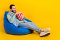 Full body size photo of funny guy enjoy entertainment lying beanbag with popcorn snack comedy film isolated on yellow