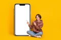 Full body size photo of young girl pointing finger empty space nomad phone touchscreen wear sweatshirt  on Royalty Free Stock Photo