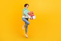 Full body size photo of young positive jump girl wear sweater hold pile gift box packages anniversary isolated on yellow