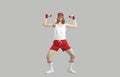 Funny skinny athlete doing fitness exercise with dumbbells isolated on gray background Royalty Free Stock Photo