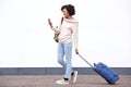 Full body smiling african american travel woman walking with mobile phone and suitcase boy white wall Royalty Free Stock Photo