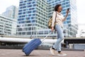 Full body smiling african american woman walking with mobile phone and suitcase outdoors Royalty Free Stock Photo