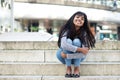 Full body smiling young Indian woman sitting on steps outdoors Royalty Free Stock Photo