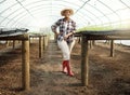 Full body of young farmer in a garden. Portrait of a proud farmer in her greenhouse. Happy african american farmer