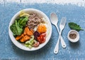 Full bowl healthy food - buckwheat, baked sweet potatoes, spinach, egg, beetroot, celery, tomatoes. Delicious diet lunch on blue b Royalty Free Stock Photo