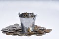 a full bucket of coins on white background with some coins spilling around. Selective focus Royalty Free Stock Photo