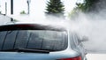 Self-service car wash. Washing a car in a carwash using a high-pressure sprayer. Gray car. Saving concept Royalty Free Stock Photo