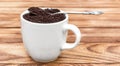 Full cup of ground coffee with spoon on wooden table Royalty Free Stock Photo